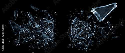 Sharp shards of broken glass exploding and flying through the air, isolated on a black background.