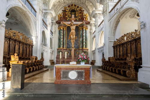 Kircheninnenraum mit Kruzifix und reich geschnitztem Chorgestühl