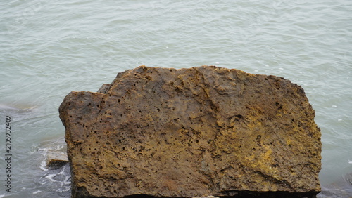 Large dark brown rock near the ocean water, natural landscape photography , nature concept with copy space