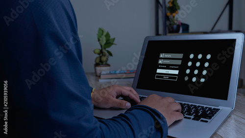 Fotografie Over the shoulder view of a man typing on laptop keyboard with virtual secure login page, username, password fields and numeric pin code keypad