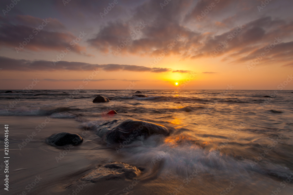 Obraz premium Sunset over rocky beach and gentle waves