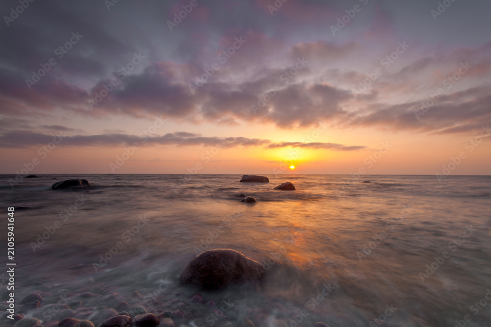 Obraz premium Sunset over rocky beach and gentle waves