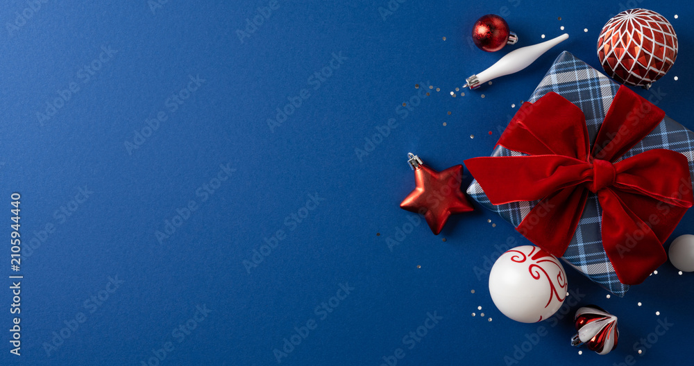Fototapeta premium Christmas gift with red bow and ornaments on blue banner background for Merry Christmas and happy New Year