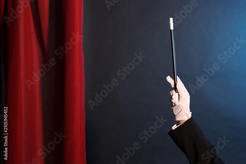 Foto Magician showing trick with wand on stage, closeup