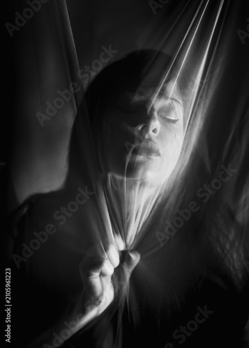 Foto Ritratto artistico in bianco e nero di donna dietro telo trasparente che tiene s