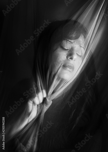 Bild auf Leinwand Ritratto artistico in bianco e nero di donna dietro telo trasparente che tiene s