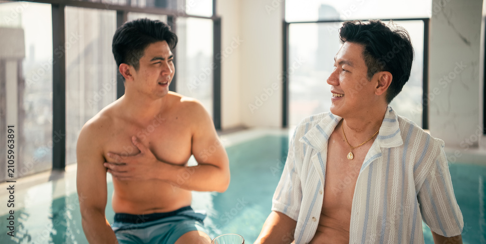Fototapeta premium Gay couple enjoying conversation by a rooftop swimming pool