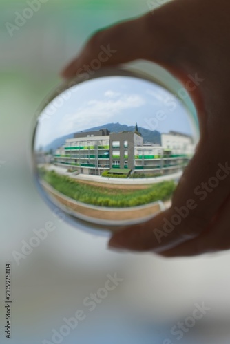 Photography Hand holding a crystal ball reflecting an upside-down view of buildings and sky