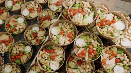 Multiple bowls of fresh salad with chicken, cherry tomatoes, and croutons arranged on a countertop, showcasing vibrant colors and textures in a kitchen setting