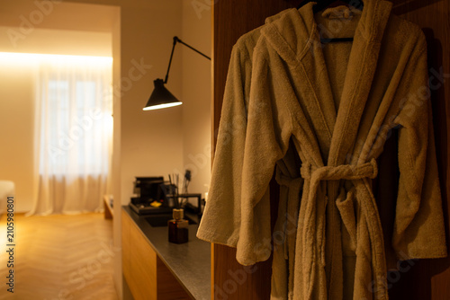 Quadro su tela Beige terry cloth bathrobe hanging on a hanger in a hotel wardrobe with blurred