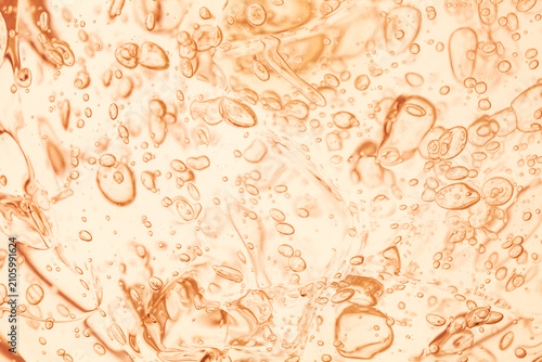 Abstract macro background of orange cosmetic gel texture with clear oxygen bubbles. Moisturizing skincare product orretinol serum close-up, liquid drops pattern.
