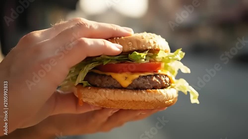 Delicious cheeseburger held by hands, showcasing a juicy patty, melted cheese, crisp lettuce, and ripe tomato on a toasted bun, ready for a satisfying, quick meal