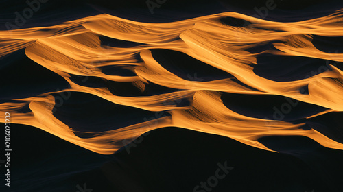 Abstract waves of golden light against a dark background, creating a mesmerizing flow pattern perfect for modern design projects.