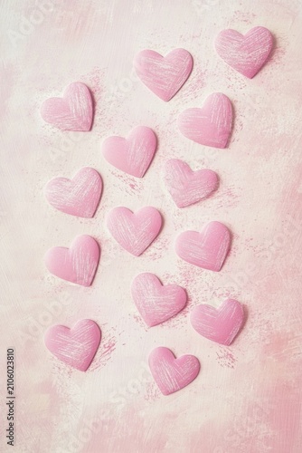 Scattered pink heart-shaped confetti on a textured rose background