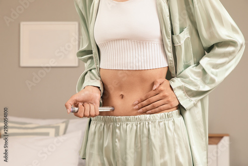Woman in pajamas injecting ...