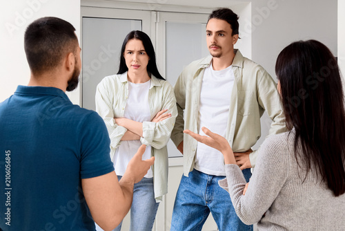Four young adults engaged in a serious discussion or argument, expressing var...