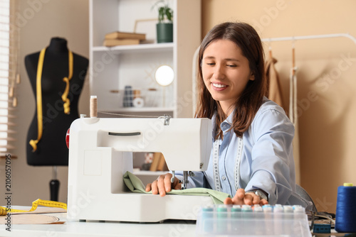 Smiling young woman sewing ...