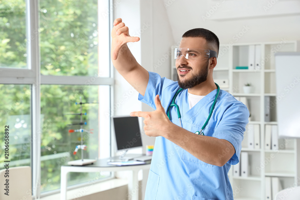 Fototapeta premium Male doctor in AR glasses showing something at hospital
