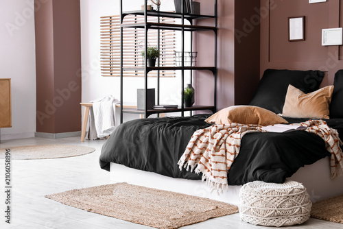 Obraz na płótnie Interior of modern bedroom with cozy bed, black bedclothes, pouf and shelving un
