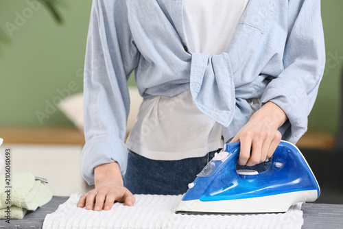 Young woman ironing clean c...