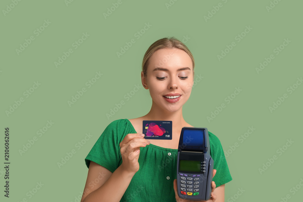 Obraz premium Pretty young woman with credit card and payment terminal on green background