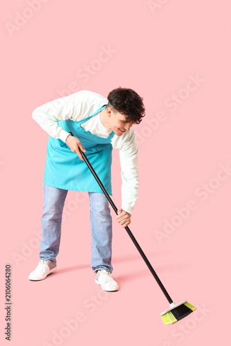 Male janitor with broom on pink background
