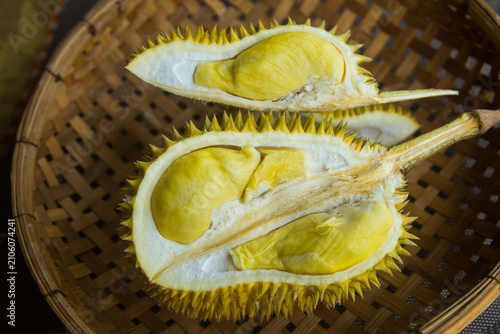 A durian, cut in half, is placed on a woven bamboo basket. Durian is a fruit found in Southeast Asia.