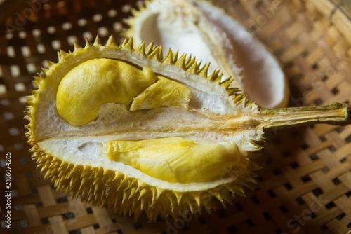 A durian, cut in half, is placed on a woven bamboo basket. Durian is a fruit found in Southeast Asia.