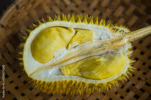 A durian, cut in half, is placed on a woven bamboo basket. Durian is a fruit found in Southeast Asia.