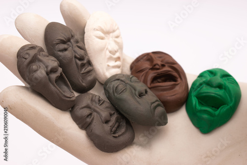 Wooden hand holding colorful miniature faces with different emotional expressions