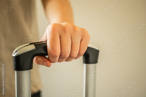Obraz na płótnie Close-up of a person's hand grasping the retractable telescopic handle of a rolling suitcase, ready for departure or travel, with copy space