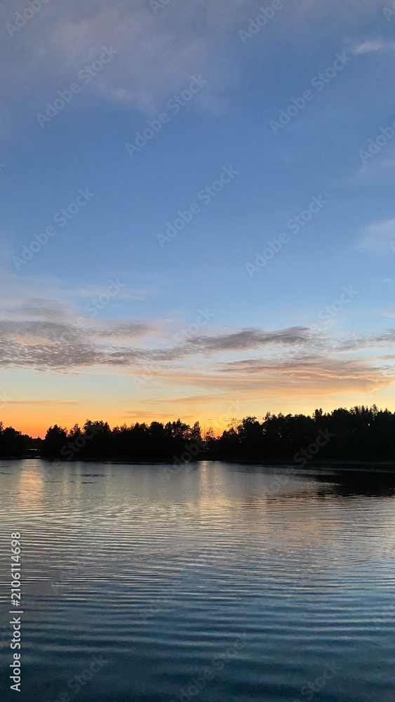 Obraz premium Tranquil Lake Landscape at Sunset with Tree Silhouettes and Water Reflection