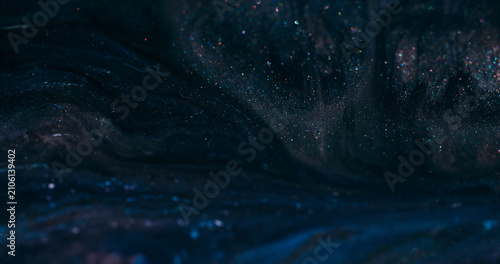 Dark ink flow. Defocused sparkling texture. Black blue night color dye blending in glitter cosmic liquid wavy abstract background.