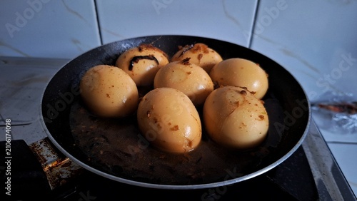 Fotografi Boiled brown eggs simmer in a hot frying pan, highlighting traditional cooking techniques for preparing healthy protein meals in a modern kitchen