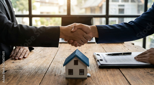 Businessmen shaking hands over real estate contract and house model