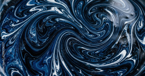 Swirling liquid paint texture with deep navy blue, black, and white colors in a fluid marble pattern, macro