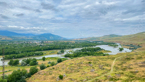 Kura River branches across a valley below Uplistsikhe in an elevated panoramic shot, linking wooded floodplains