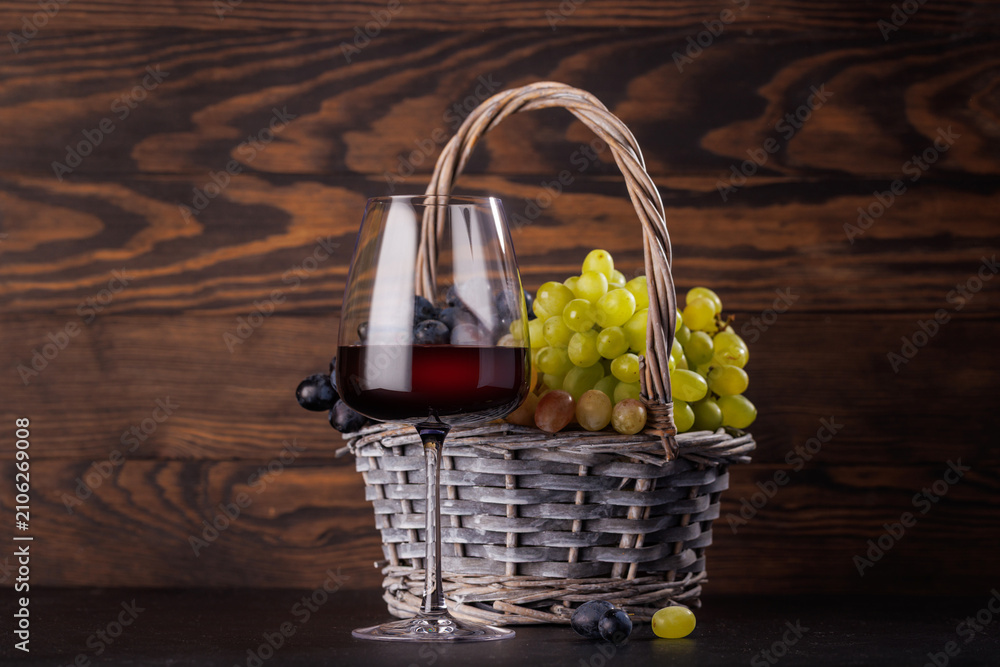 Obraz premium Red wine glass and basket of fresh grapes