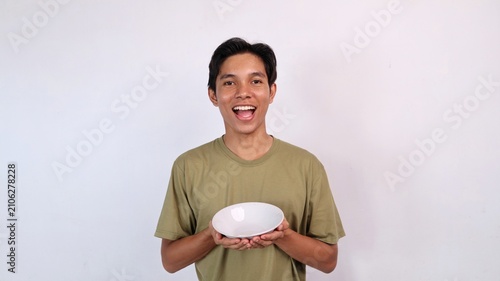 Obraz na płótnie smiling young asian man holding empty bowl
