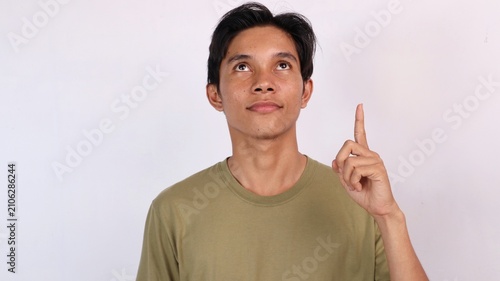 Foto young asian man pointing and glancing up against