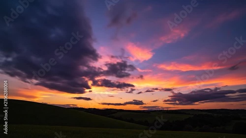 Vibrant golden sun rays shine over the rolling green hills at sunset