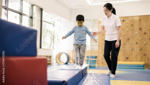 Child Practicing Balance Skills with Instructor in Gym Setting