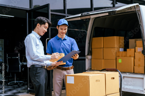 Картината върху платно Two delivery workers checking a clipboard beside a van loaded with cardboard box