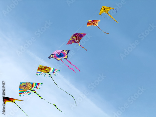 Colorful kites flying in a row against a clear blue sky during a sunny day