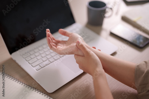 Bild auf Leinwand Asian woman massaging painful wrist experiencing carpal tunnel syndrome while wo