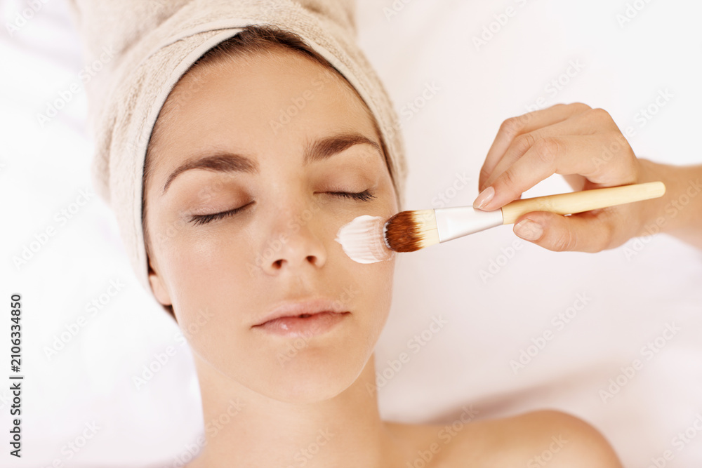Obraz premium Hands, facial and brush with woman in spa for pore detox, skincare and deep cleaning cosmetics. Clay treatment, beauty glow and face mask with above of person in salon for purifying minerals