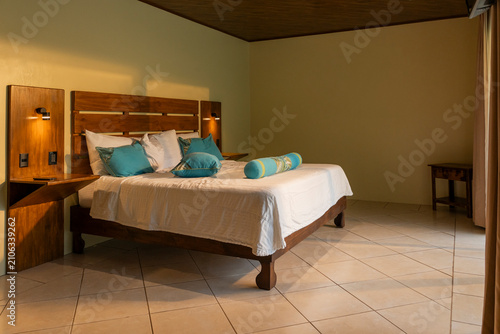 Canvastavla Cozy bedroom interior with wooden bed and turquoise pillows