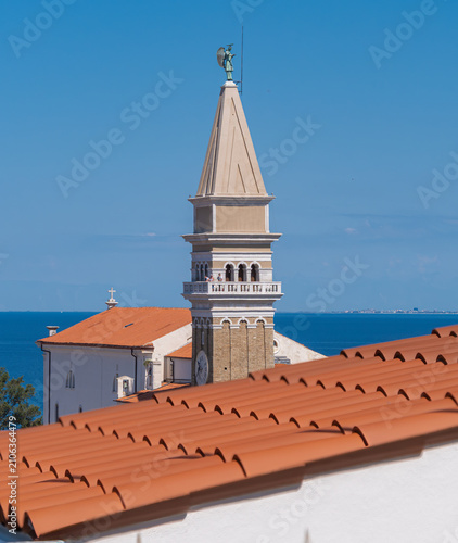 Church tower above tiled roofs by the sea