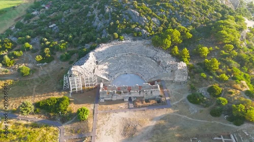 Gelemis, Turkey. Patara Ancient Theatre, monumental semi-circular stone amphitheatre carved into forested hillside, low angle aerial view at golden hour. Aerial View, MasterShots, Rocket