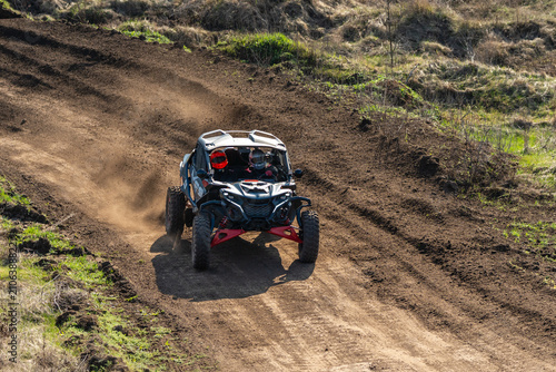 Off-road racing utv driving on dirt track creating dust